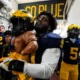 Josaiah Stewart carries the Paul Bunyan Trophy for Michigan Football