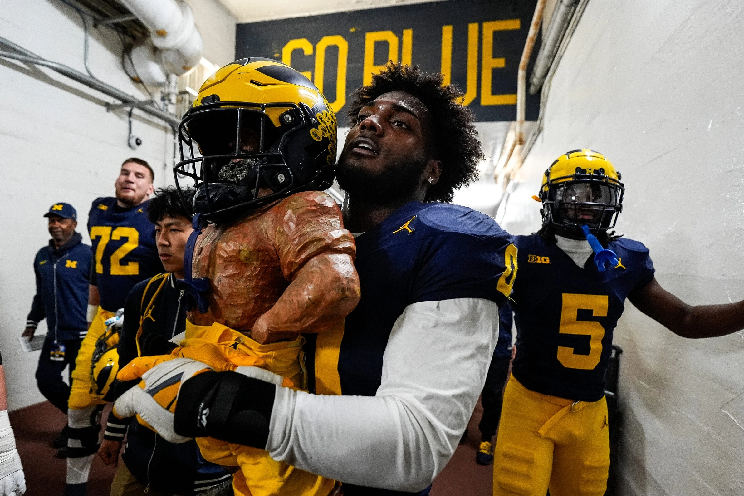 Josaiah Stewart carries the Paul Bunyan Trophy for Michigan Football